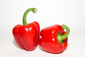 Two ripe red  peppers on over white