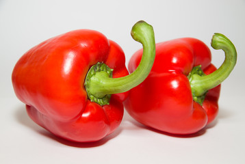 Two ripe red  peppers on over white