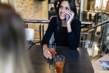 Beautiful brunette talking on phone in cafe