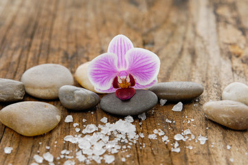 Fototapeta na wymiar pink orchid and stones with pile of salt on old wood texture
