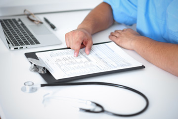 Portrait of unknown male surgeon doctor sitting at the table in hospital office, stethoscope