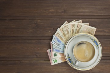 Cup of coffee and money. Valid banknotes on a wooden table. The problem of corruption.
