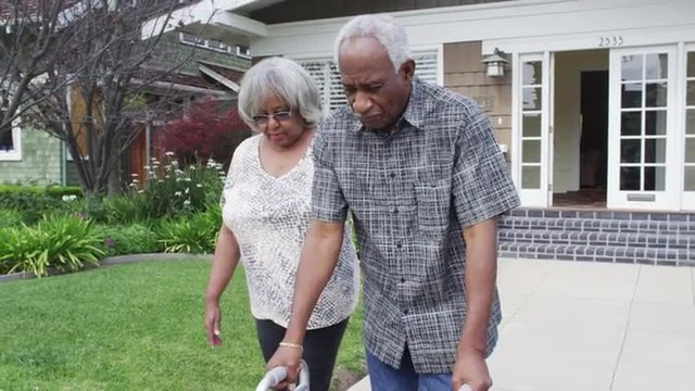Mature black couple walking together with walker