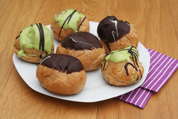 bignè al cioccolato e pistacchio su piatto su tavolo di legno