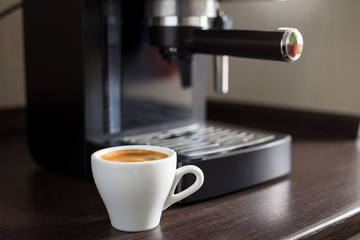 White ceramic cup of espresso with coffee machine