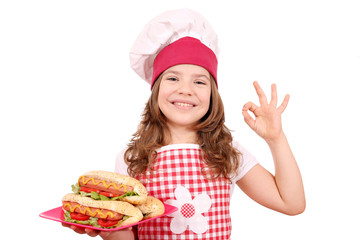 happy little girl cook with hot dogs and ok hand sign