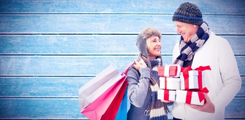Composite image of festive mature couple holding christmas gifts - Powered by Adobe