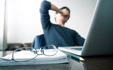 man with his hand holding his face taking a brake from working with laptop computer and notebook...