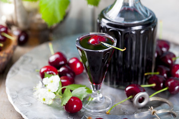 Cherry homemade liquor in a vintage bottle with fresh cherries.