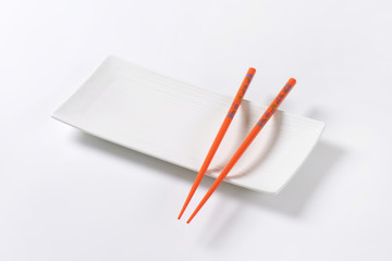 Orange chopsticks on empty sushi plate