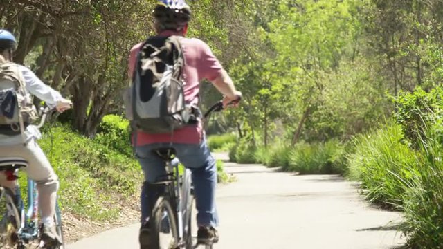 Active senior couple riding bikes on trail at park