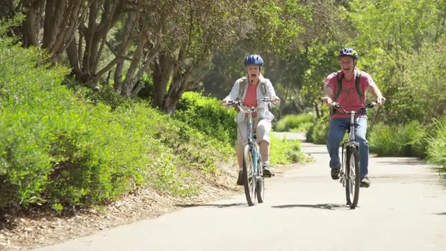 Senior couple happily riding bikes outdoors on trail