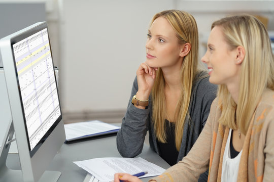 zwei kolleginnen schauen auf eine tabelle am computer