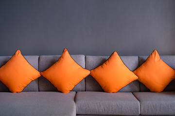 orange scatter cushion or backrest pillow on grey sofa.