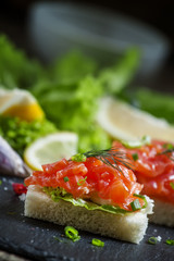 Small sandwiches canapes with salty salmon,  soft cheese and gre