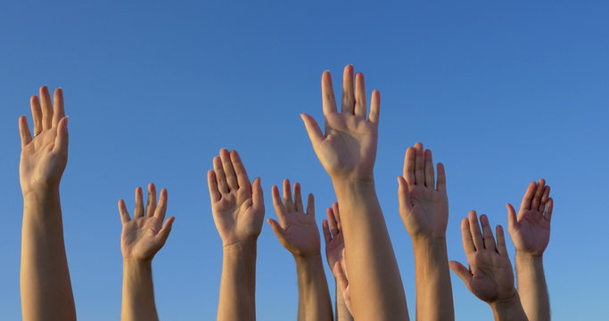 Raised hands against blue sky