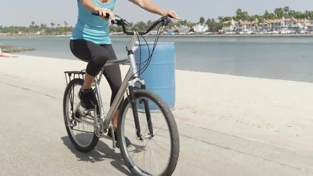 Young healthy woman riding bike along river