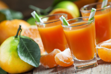 Fresh juice of ripe mandarins in a small glass with striped stra