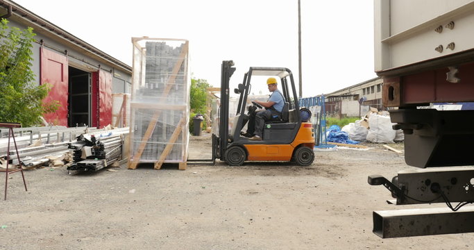 Forklift operator picking up cargo in front of a warehouse