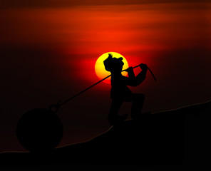 Man with pulling a heavy load ball silhouette with sunset