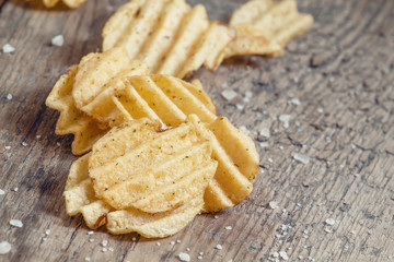 Golden corrugated potato chips on an old wooden table, selective