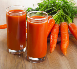 glasses of carrot juice and carrots on a wooden table