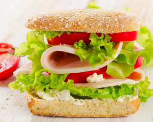 Sandwich with  fresh tomatoes on  a wooden table