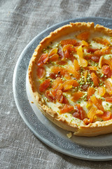 a round tart with whipped cream, dried apricots and pistachio nu