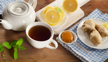 Teapot and cup of tea with lemon, ginger, honey  and mint