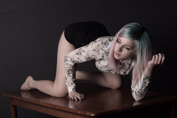 Fototapeta na wymiar Girl with multi-coloured hair crawling on the table