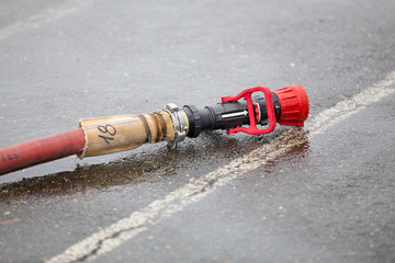 fire hose with nozzle with red on wet asphalt - 96092473