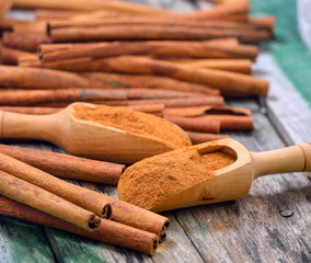 Cinnamon sticks and powder cinnamon in the spoon on table