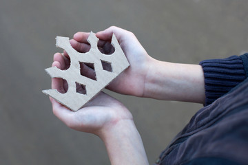 young homeless boy holds a cardboard crown