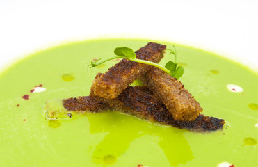 pea soup with croutons on a white dish at restaurant
