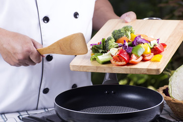 Chef putting vegetable to the pan