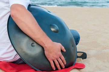 Busker hold the Hang or handpan with sea on background. The hang is a traditional ethnic drum...