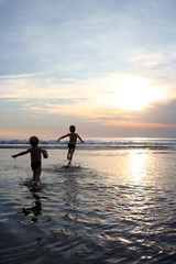 Young children on the ocean at sunset