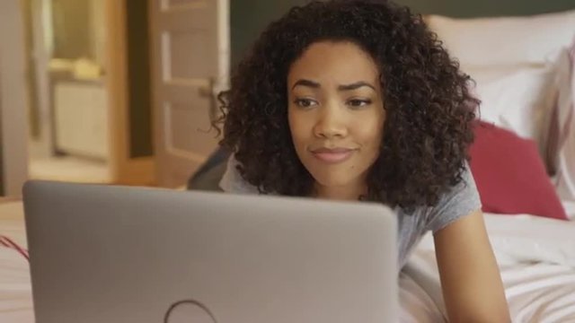 Black woman browsing the web on laptop at home