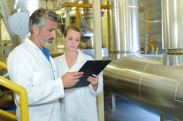Man and woman in factory holding clipboard