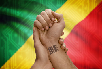 Barcode ID number on wrist of dark skinned person and national flag on background - Congo-Brazzaville