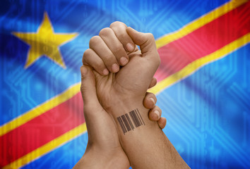 Barcode ID number on wrist of dark skinned person and national flag on background - Congo-Kinshasa