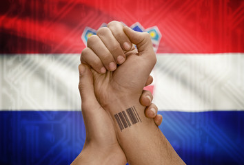 Barcode ID number on wrist of dark skinned person and national flag on background - Croatia