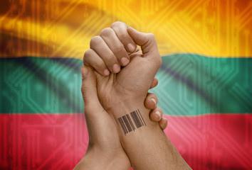 Barcode ID number on wrist of dark skinned person and national flag on background - Lithuania