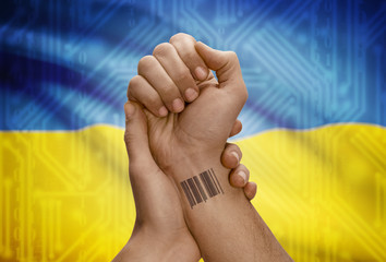 Barcode ID number on wrist of dark skinned person and national flag on background - Ukraine