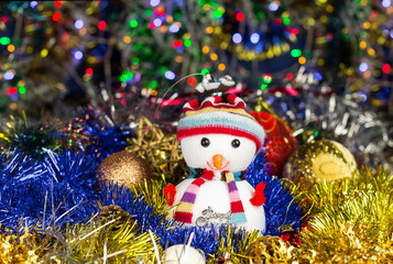 Festive snowman with Christmas balls, tinsel on blurred lights background
