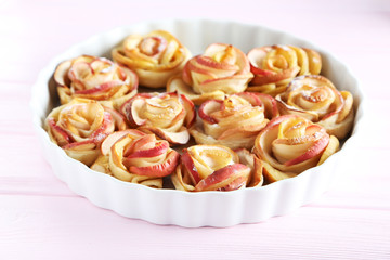 Fresh puff pastry with apple shaped roses on pink wooden table