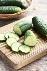 Fresh cucumbers on cutting board on grey wooden background