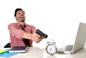 businessman in stress at office computer desk pointing hand gun to alarm clock in out of time and...