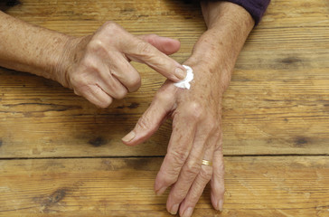 senior woman applying cream on hands