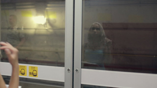 Girl standing in a subway car in front of the closed glass door